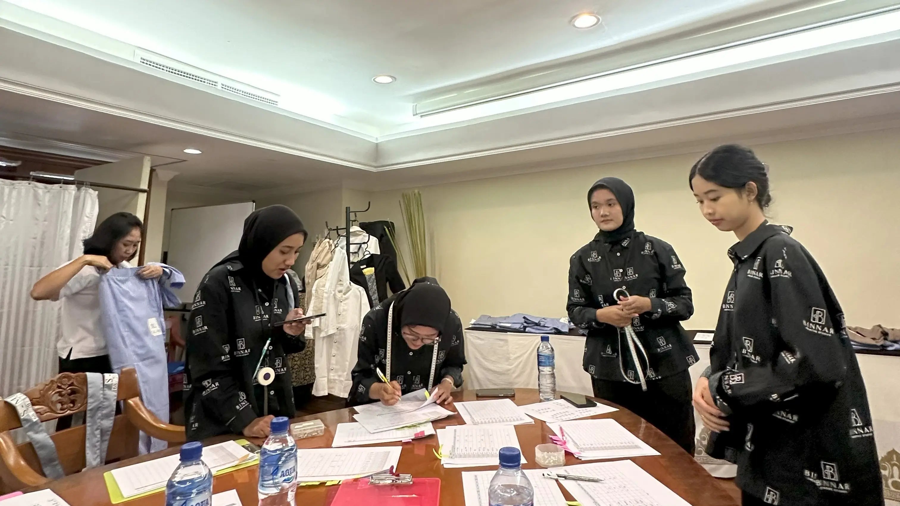 Group of women in a room with tables and chairs, engaged in an activity.
