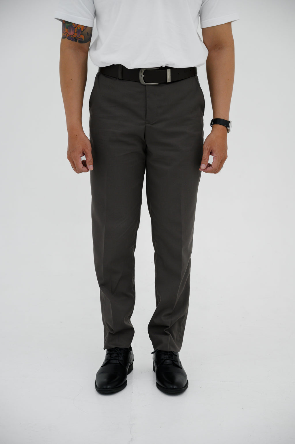Person wearing gray pants and black shoes on a white background