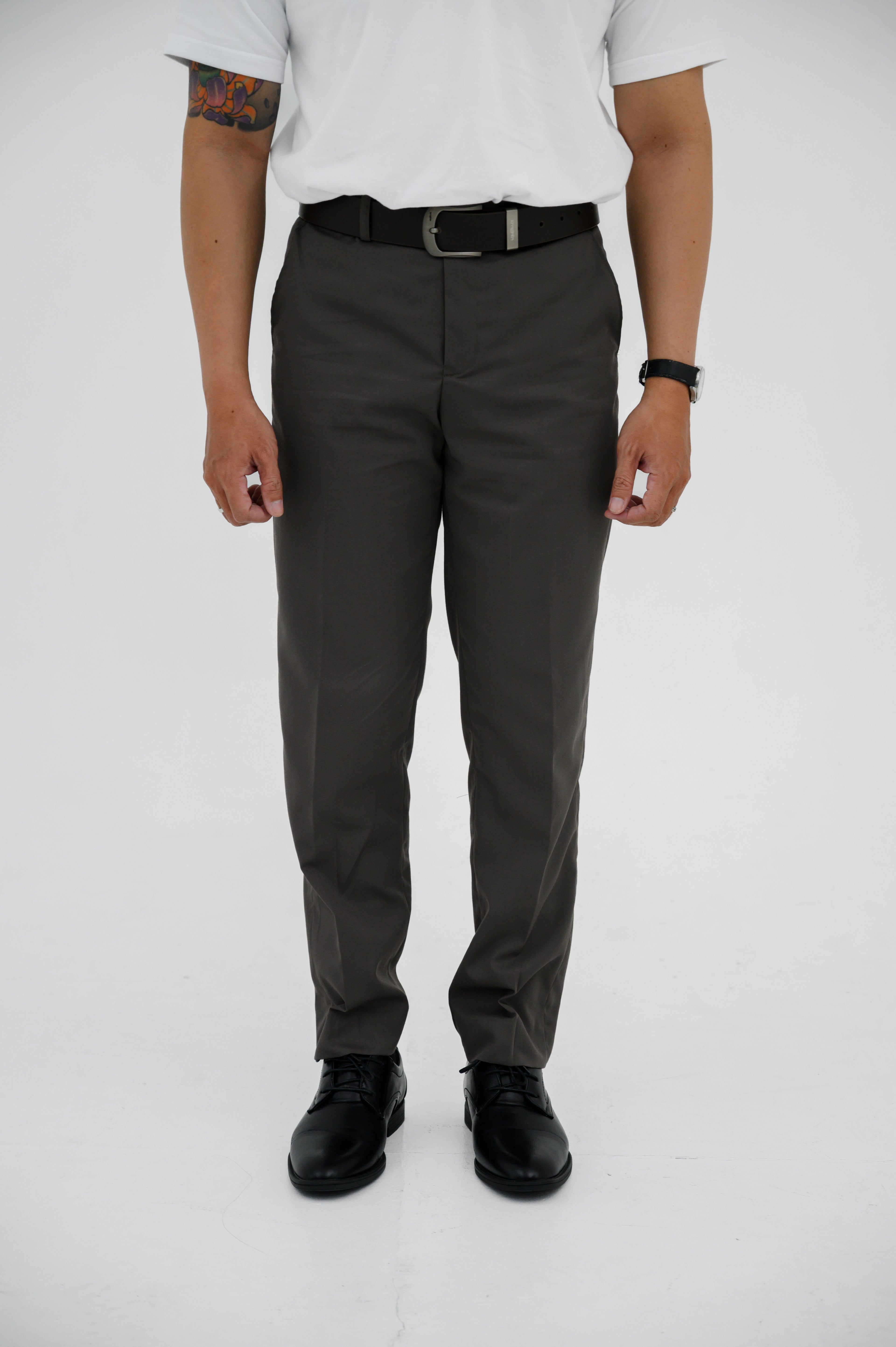 Person wearing gray pants and black shoes on a white background