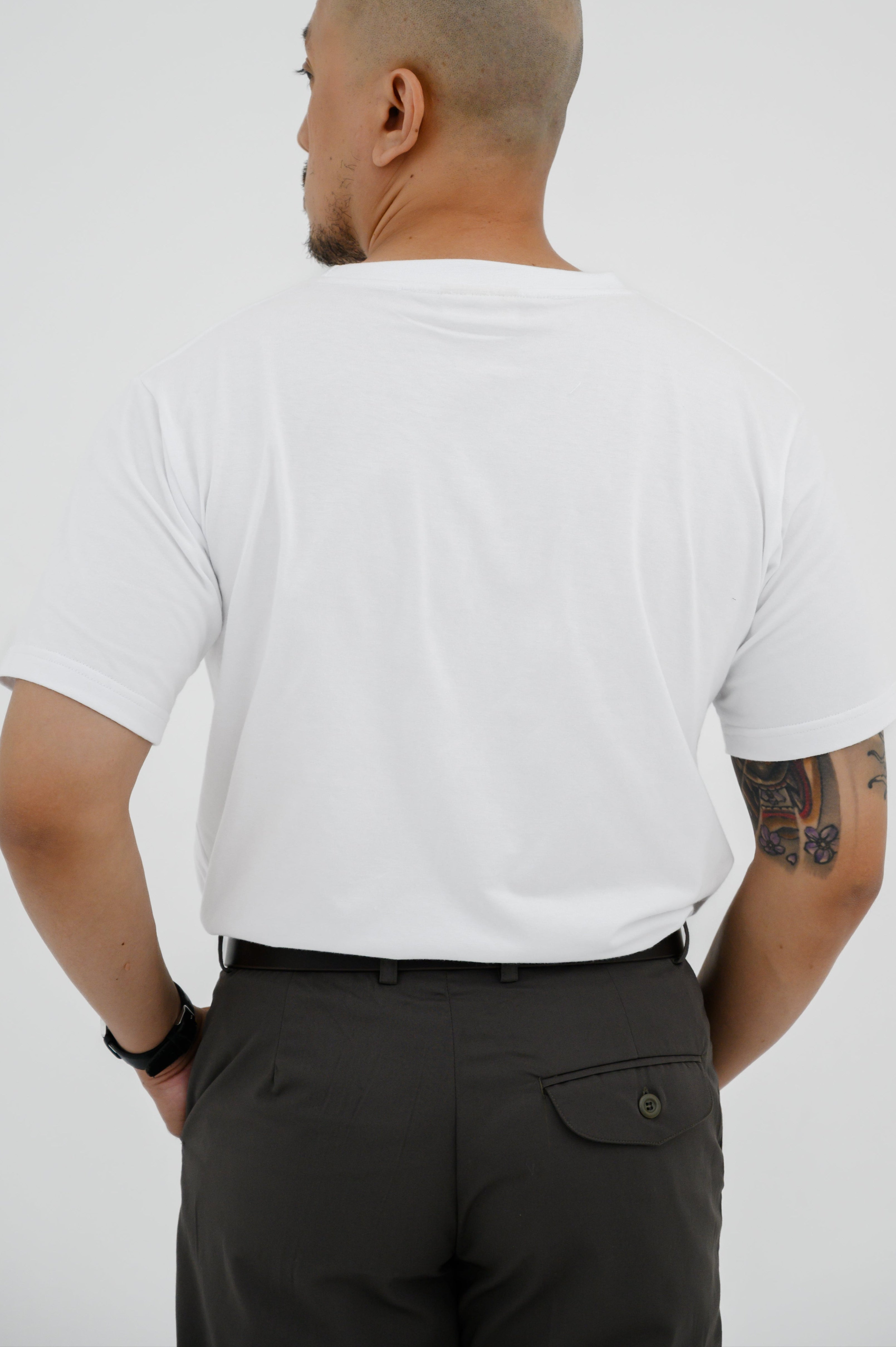 Man wearing a white t-shirt and black pants against a plain background