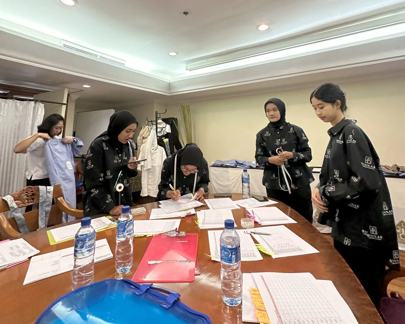 Group of people in a meeting room with water bottles and documents on a table.